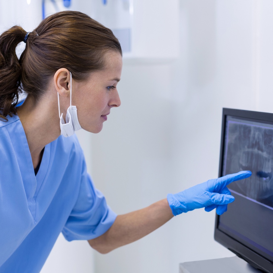 Dental assistant examining an x-ray on the monitor in clinic