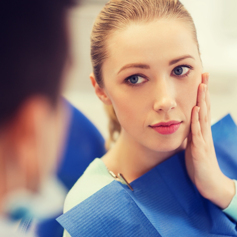 people, medicine, stomatology and health care concept - woman patient talking to male dentist and complain of toothache at dental clinic office
