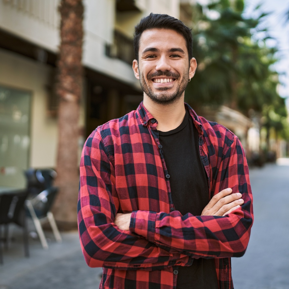 Young hispanic man smiling confident standing with arms crossed gesture at street