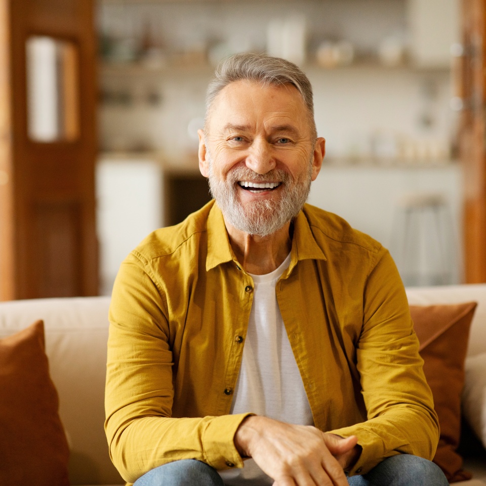 Portrait of happy older retired man laughing, looking at camera, enjoying video call or distant communicating with friends